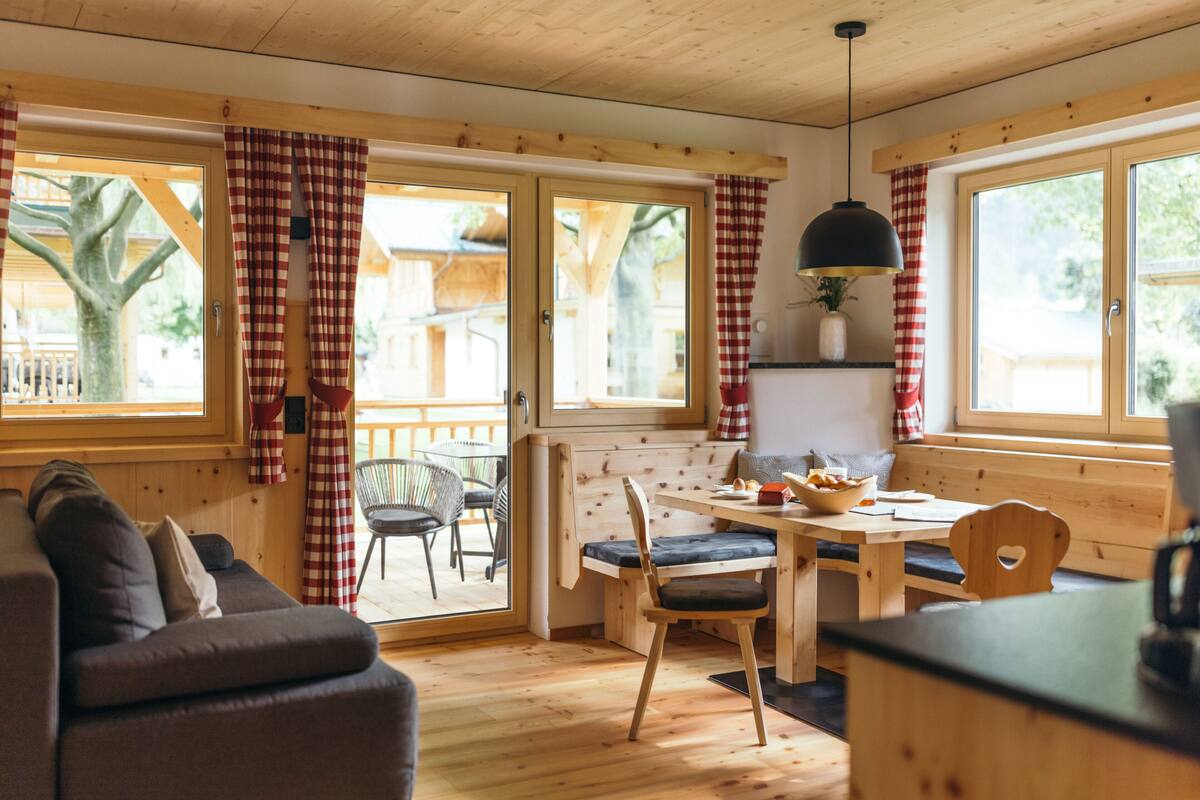 Een gezellig interieur van een chalet met een houten eettafel, stoelen en een bank.