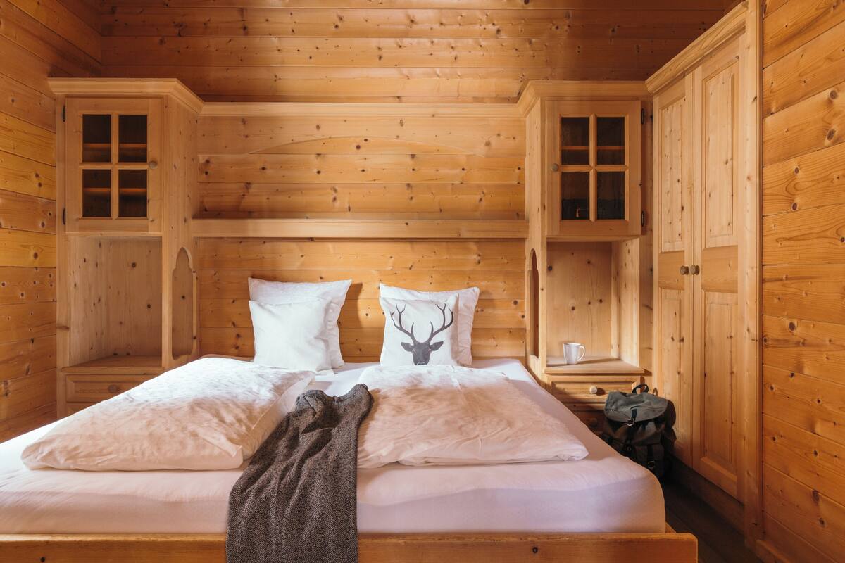 Een slaapkamer in een houten chalet, met een bed, twee nachtkastjes en een kledingkast.