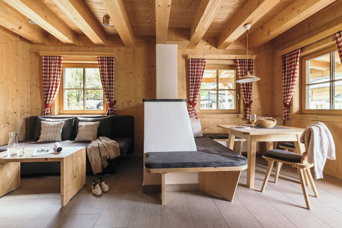 Een houten cabin met een bank, een eettafel en een bankje.