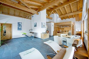 Un interior moderno con vigas de madera, una zona de recepción y un área de descanso con una mesa.