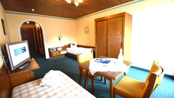 A hotel room with a bed, a desk, a chair, a television, and a wardrobe.