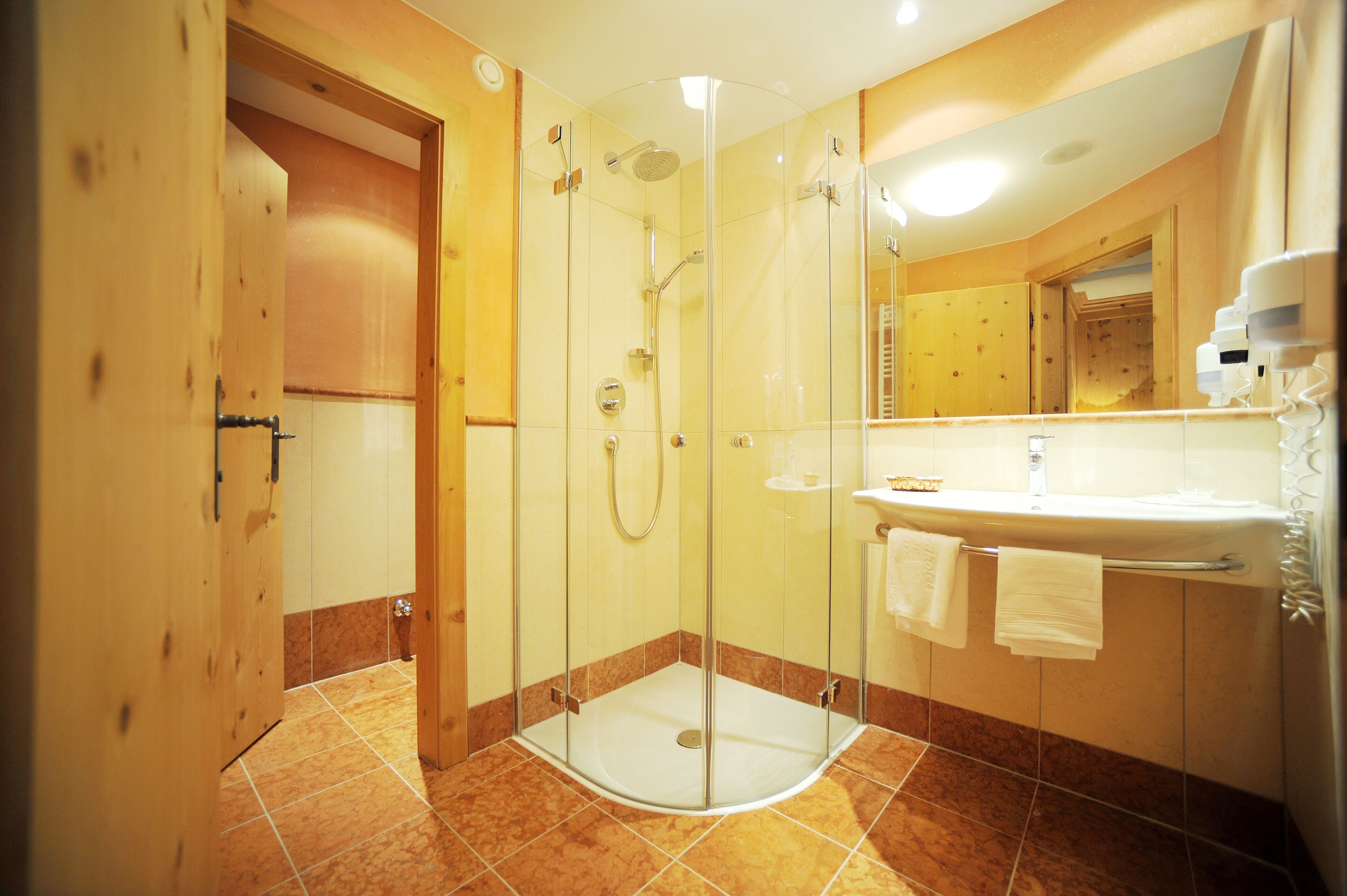 A modern bathroom with a glass-enclosed shower, a sink with a mirror, and wooden cabinets.