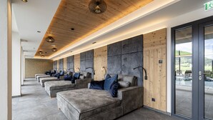 A row of grey sofas with blue cushions in a modern lobby with wooden ceiling and stone walls.