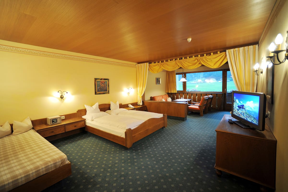A hotel room with a large bed, a sofa, a desk, and a television.