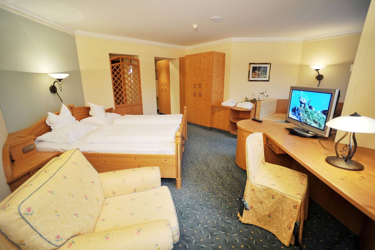 A hotel room with two beds, a desk with a television, a chair, and a wardrobe.