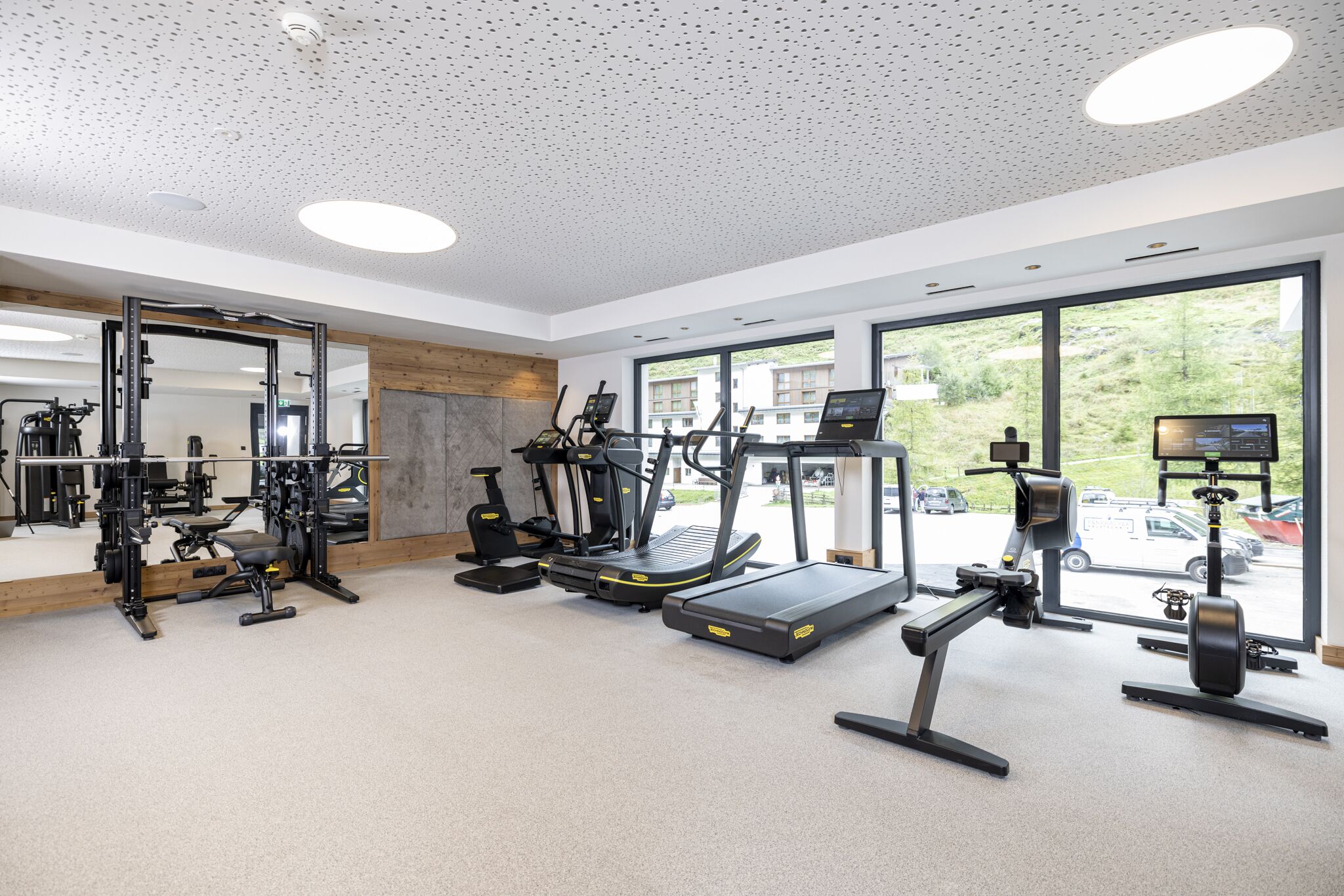 A modern gym with treadmills, elliptical machines, and weight stations.