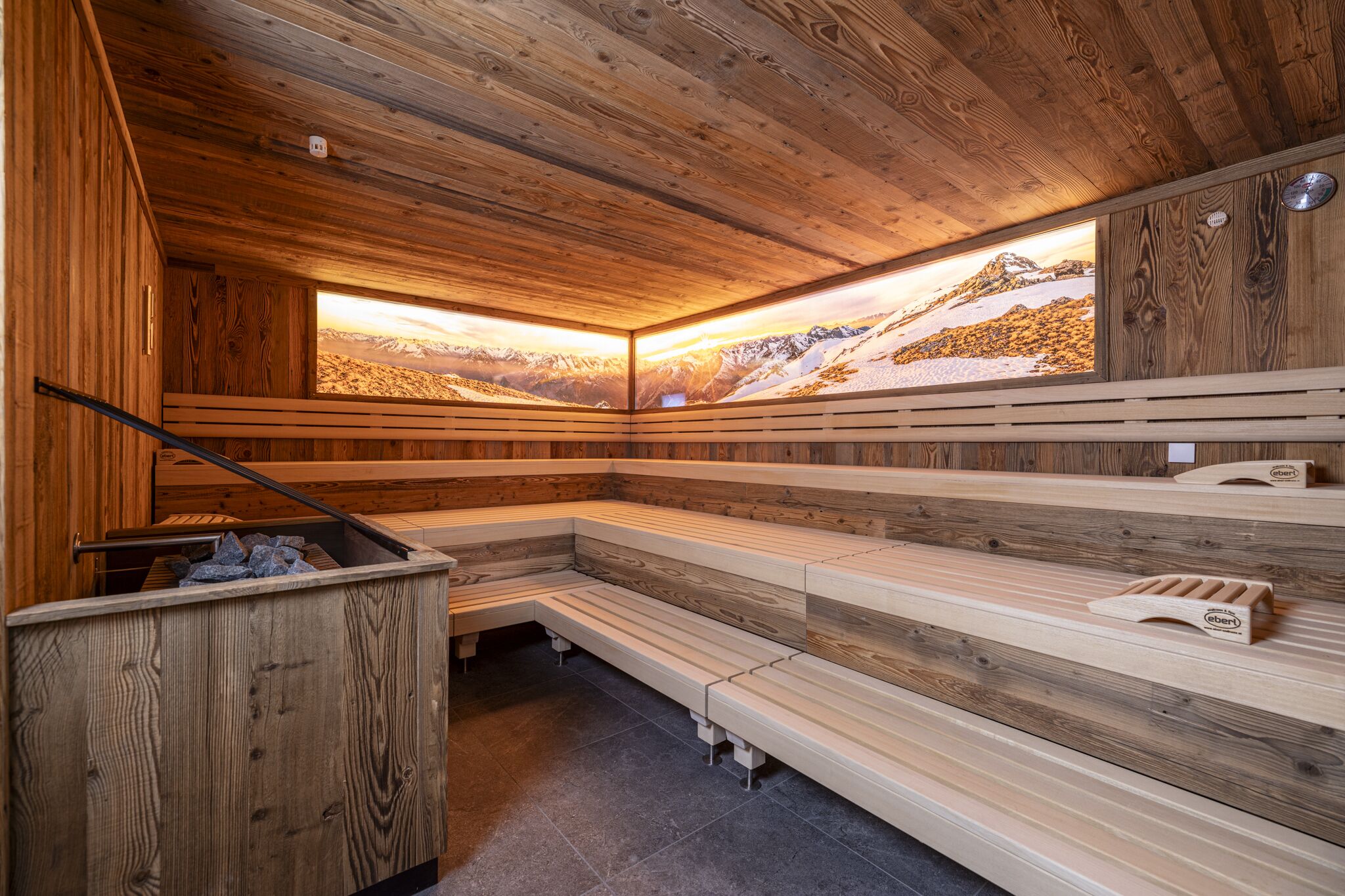 Una sauna de madera con bancos y vistas a un paisaje montañoso nevado.