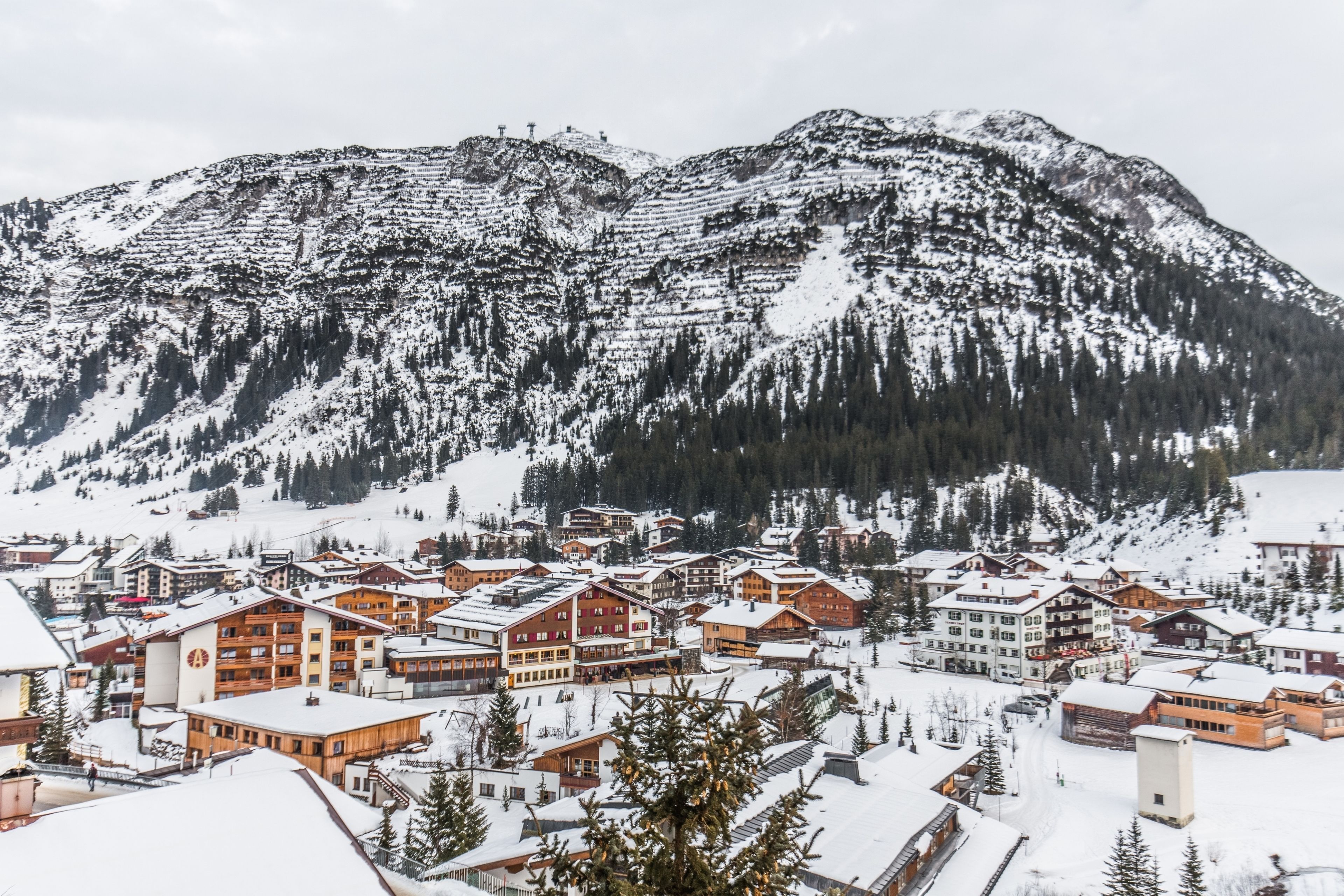 A snow-covered mountain town with wooden buildings and a ski resort in the background.