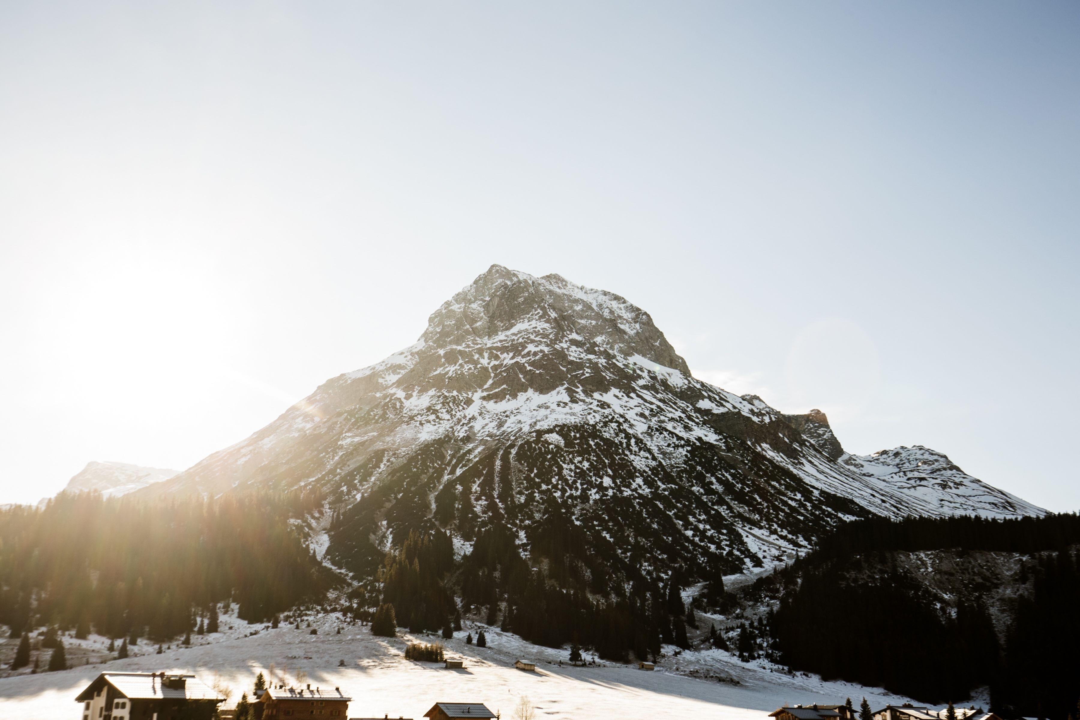 Une montagne dont les sommets sont couverts de neige, avec un petit bâtiment à son pied.