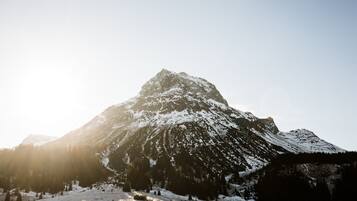 Une montagne dont les sommets sont couverts de neige, avec un petit bâtiment à son pied.