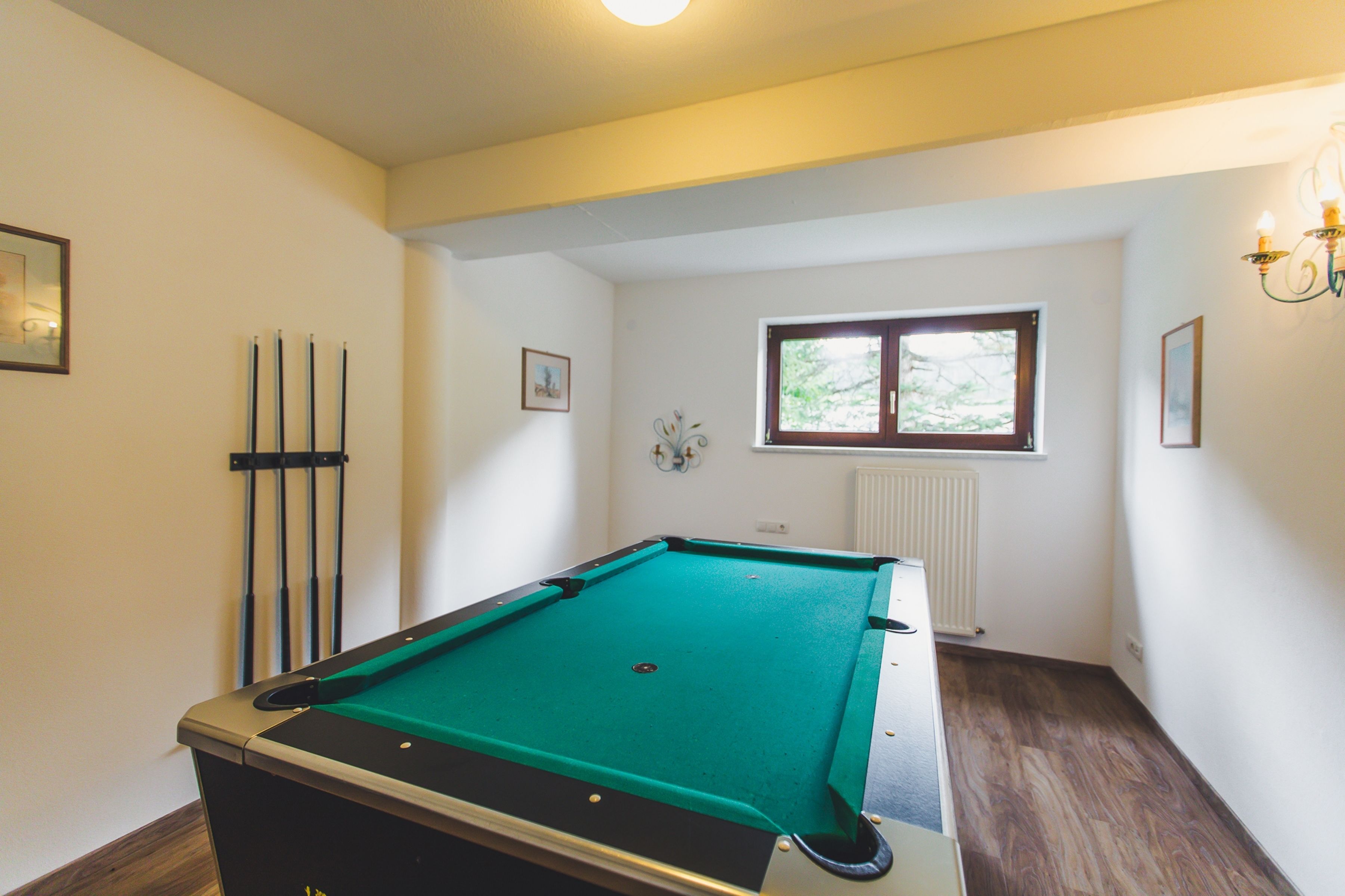 A pool table in a room with white walls, a window, and a radiator.