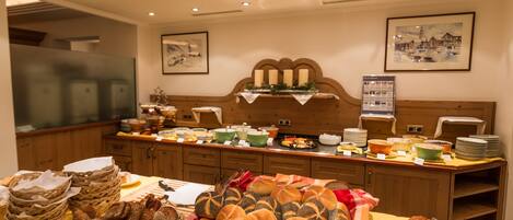 A buffet setup with various breads and pastries.