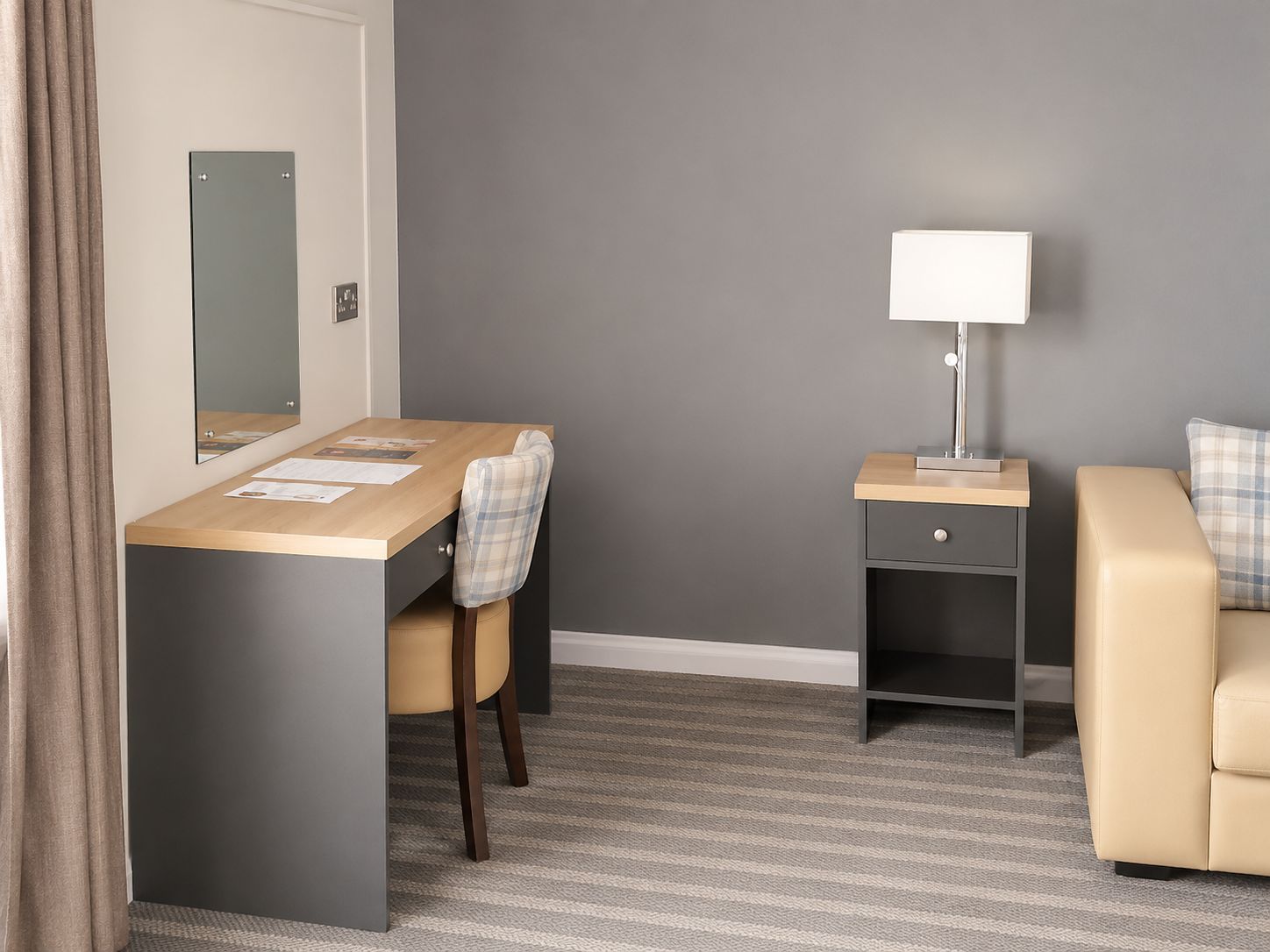 Une chambre d’hôtel équipée d’un bureau, d’une chaise, d’une table de chevet, d’une lampe et d’un canapé.