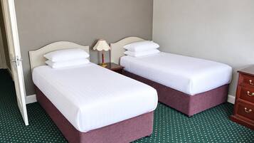 Habitación de hotel con dos camas, una mesita de noche, una lámpara y un aparador.