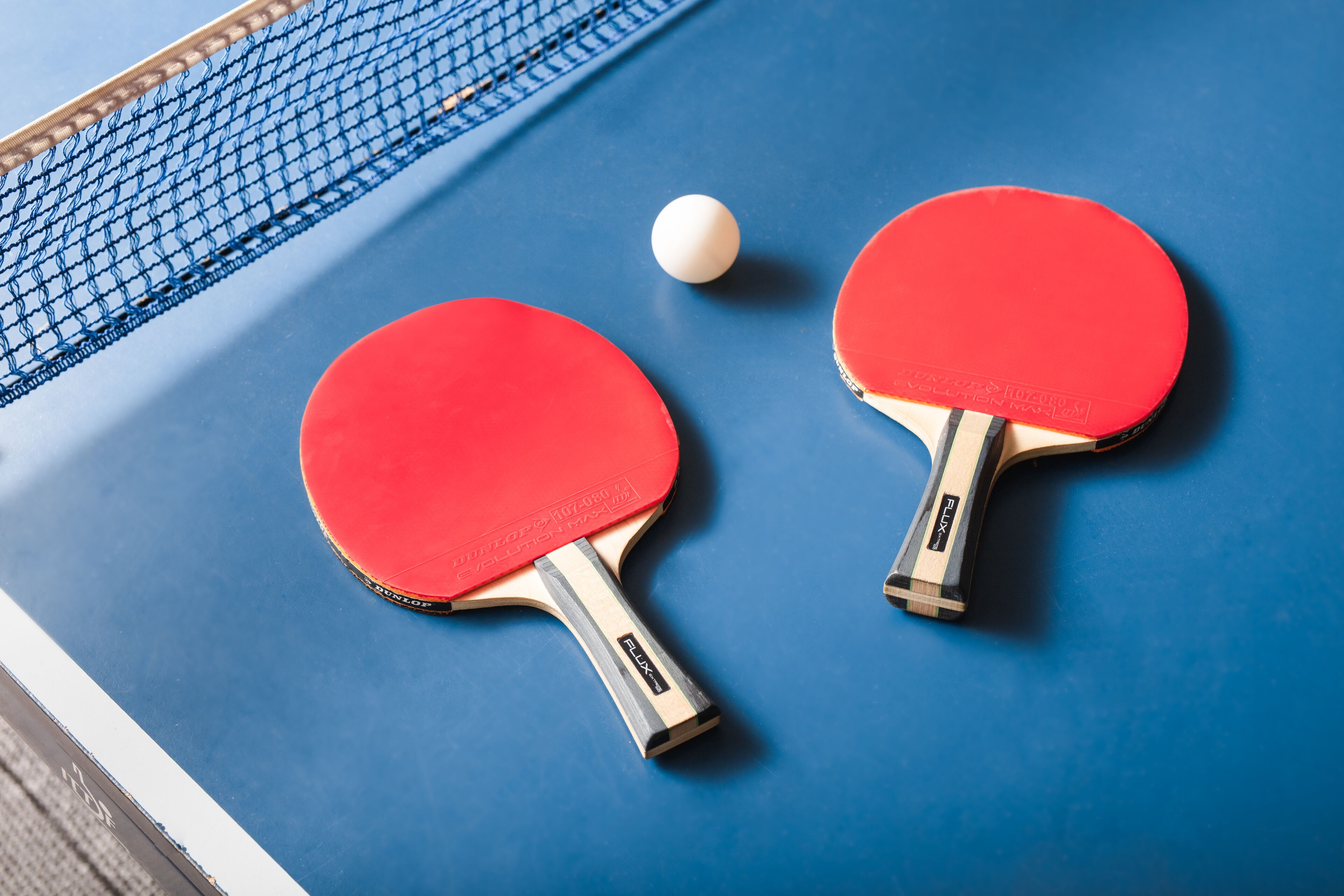 Due racchette rosse da ping pong su un tavolo blu.