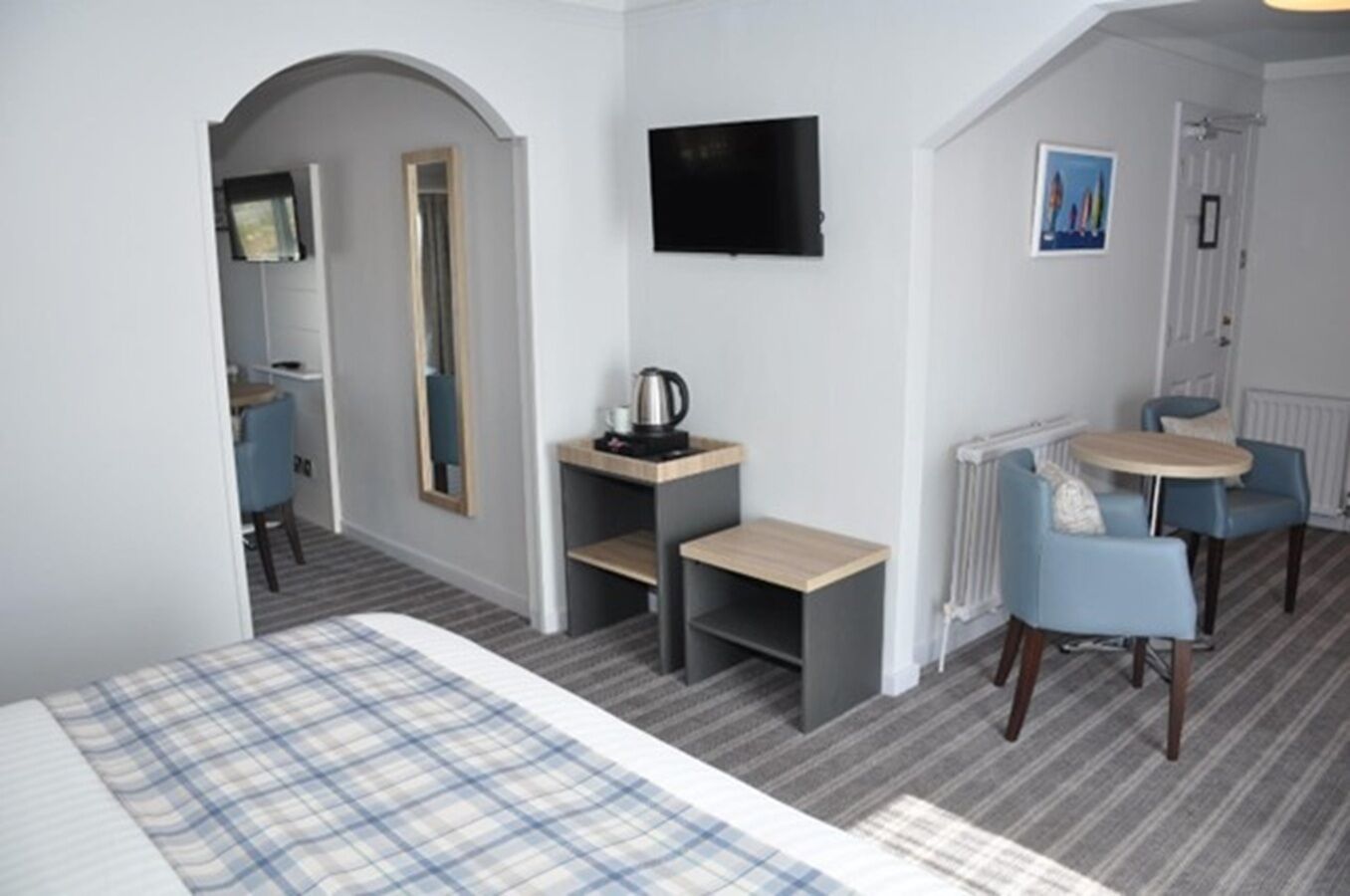 A hotel room with a bed, a desk, a chair, a television, and a small table.