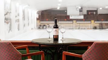 A round table with a bottle of wine and two glasses, surrounded by checkered chairs.
