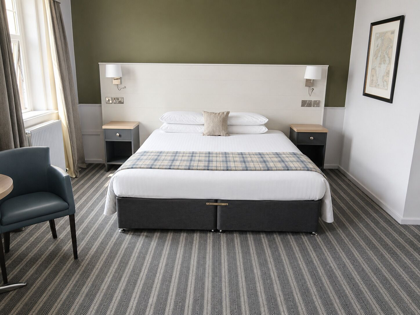 Une chambre d’hôtel avec un grand lit, deux tables de chevet, une chaise et une fenêtre avec des rideaux.
