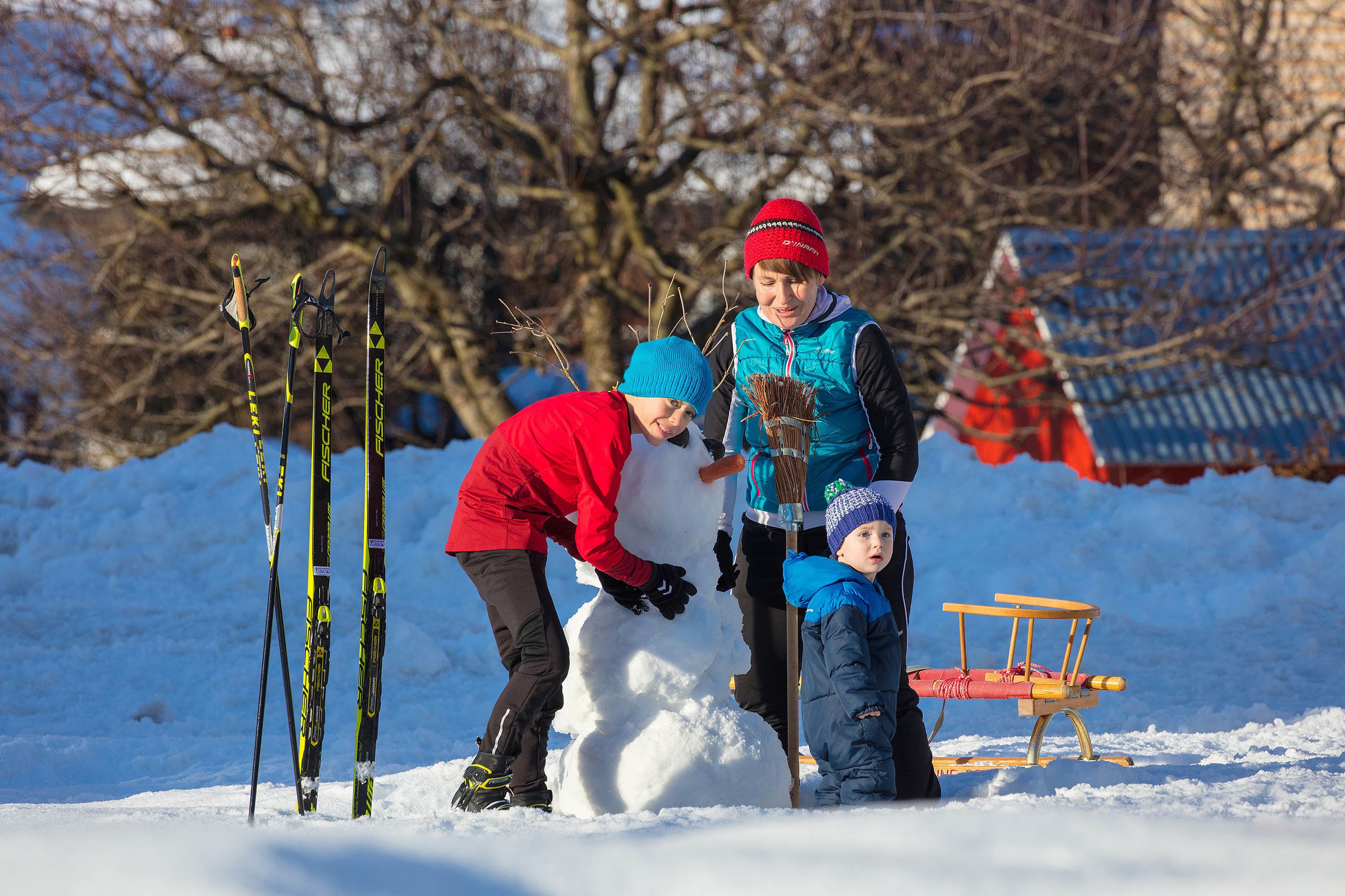 A snowy outdoor scene with a snowman, skis, and a sled.