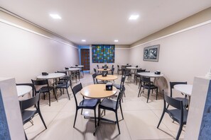 A room with multiple round tables and chairs, a colorful wall art piece, and a framed picture on the wall. - Hotel El Pilar by Bsb Inn (Brasília)