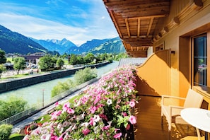 A balcony with a view of a river and mountains. - Hotel Englhof (Zellberg)