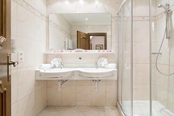 Un baño moderno con dos lavamanos, una cabina de ducha de vidrio y un espejo grande sobre los lavamanos.