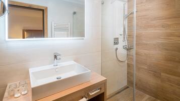 Un bagno moderno con uno specchio grande, un lavandino bianco e una cabina doccia in vetro.