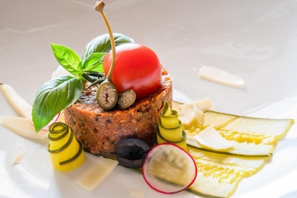 A plated dish with a cherry, basil, and pickles. - Hotel Englhof (Zellberg)
