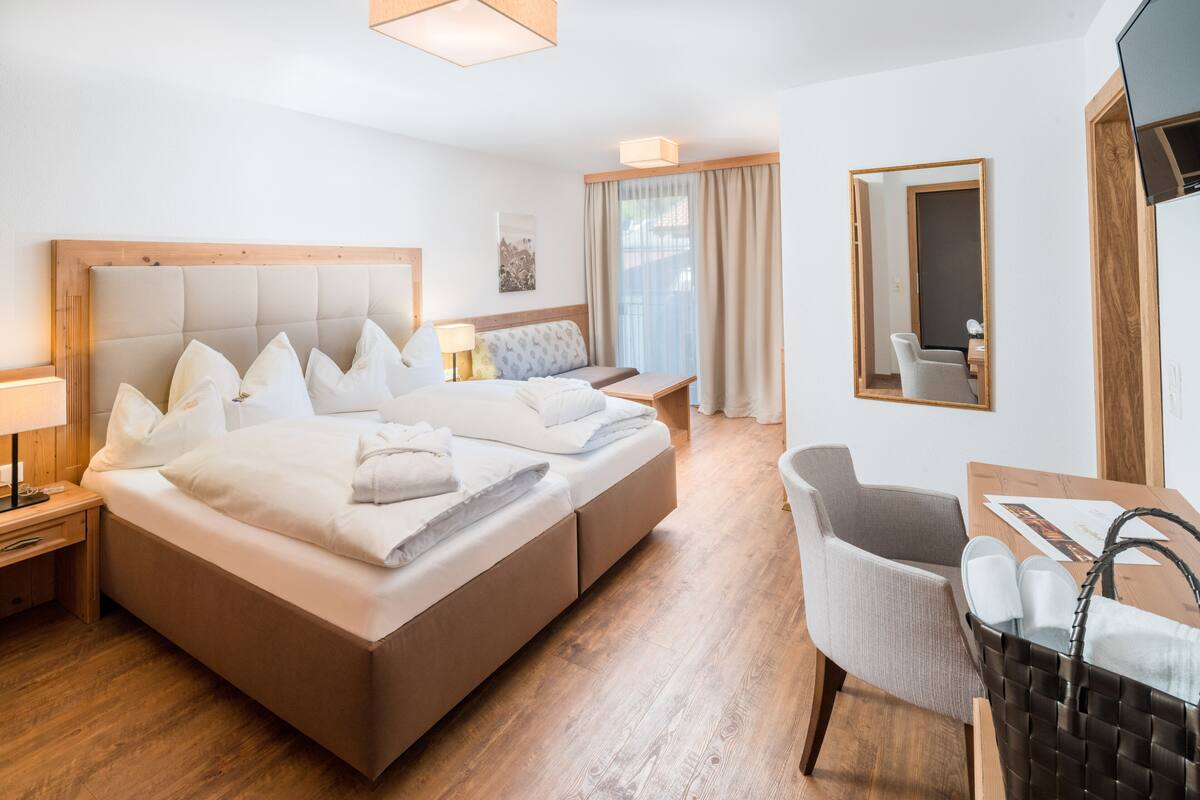A hotel room with a large bed, a desk, a chair, and a TV.