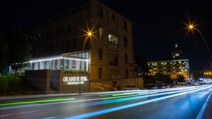Un hôtel avec une enseigne indiquant « GRAND HOTEL CENTRAL PARK » et une vue sur une rue où l’on aperçoit des traînées de lumière laissées par les véhicules en mouvement.