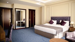 Une chambre d’hôtel avec un grand lit, un bureau, une chaise et une armoire.