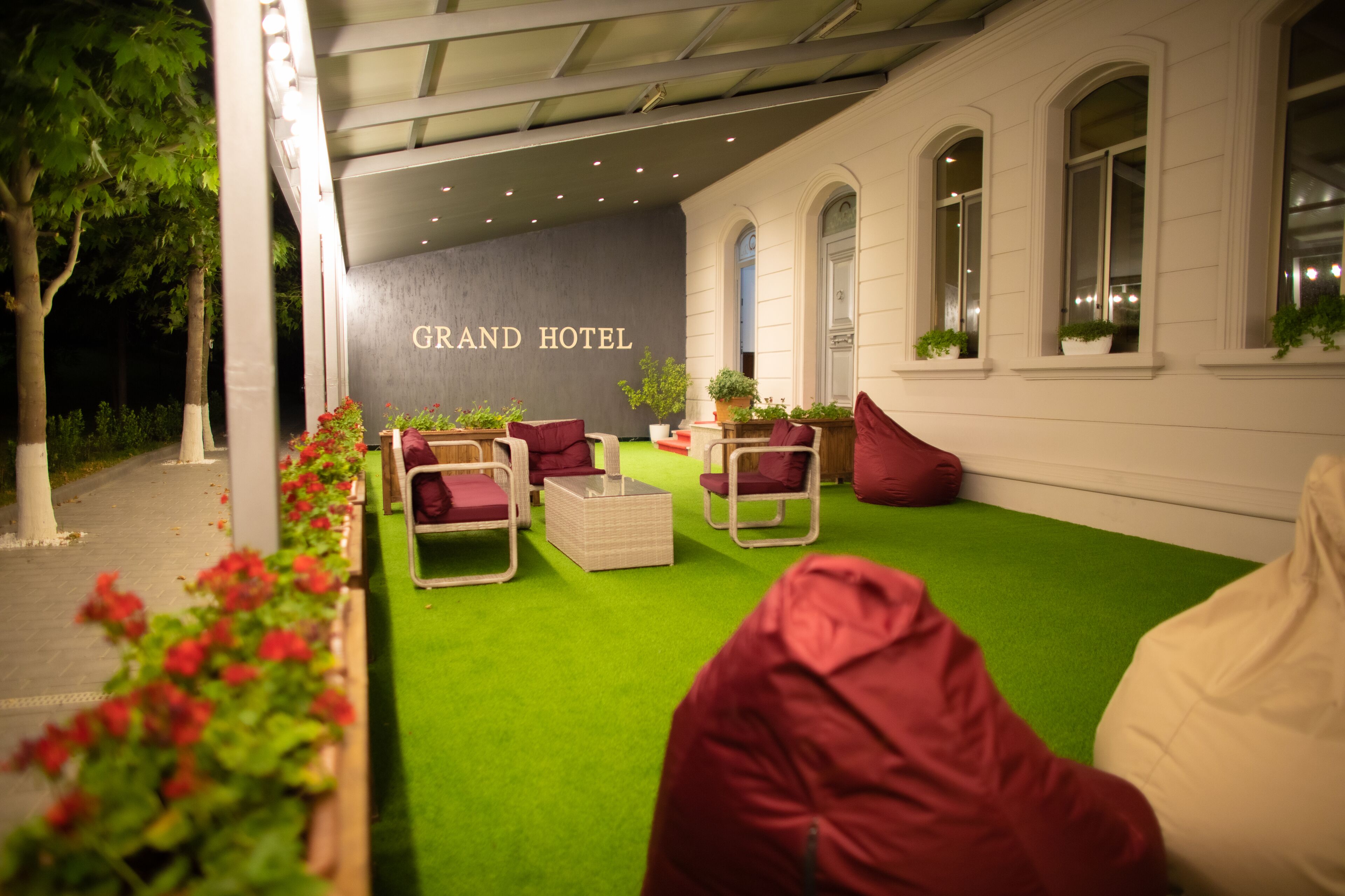 An outdoor seating area with green artificial turf, red and white furniture, and potted plants.