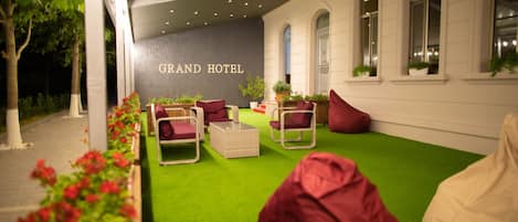 An outdoor seating area with green artificial turf, red and white furniture, and potted plants.