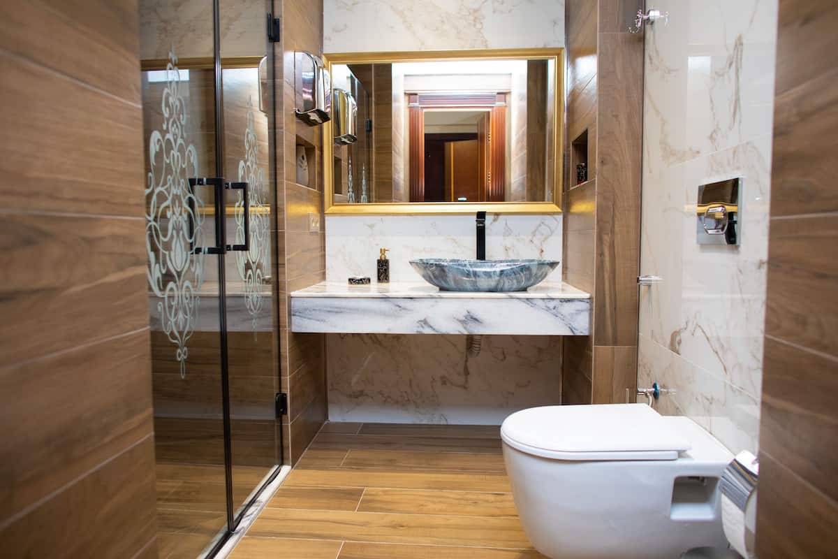 Ein modernes Badezimmer mit Duschkabine aus Glas, Marmorwaschtisch und weißer Toilette.