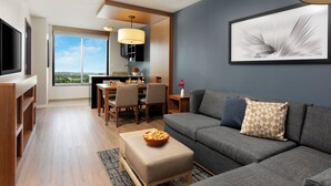 A modern living room with a sofa, a dining area, and a TV. - Hyatt Place Bayamon (Bayamon)
