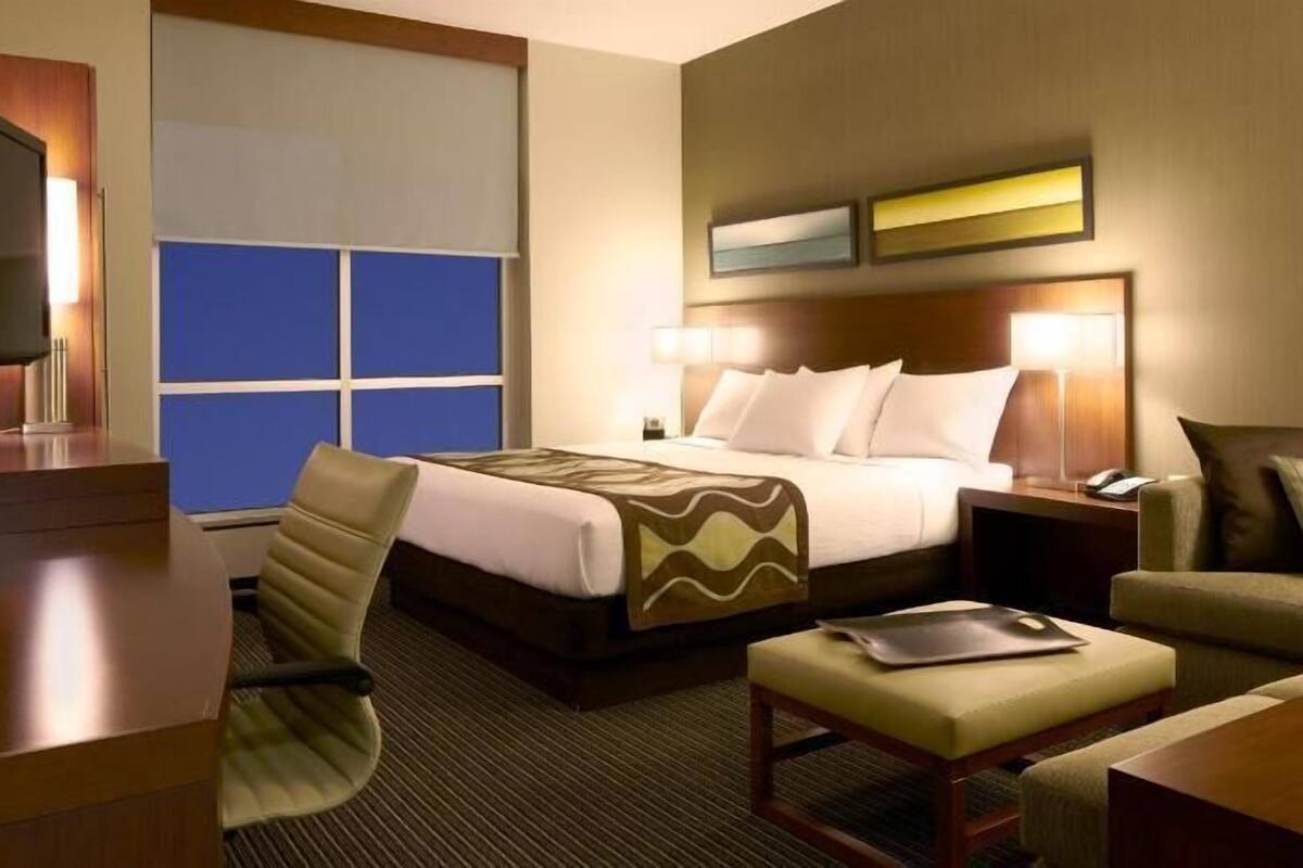 Een hotelkamer met een bed, bureau, stoel, bank en televisie.