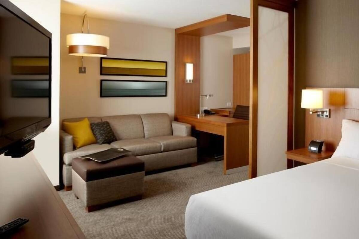 Een hotelkamer met een bed, bureau, bank en televisie.