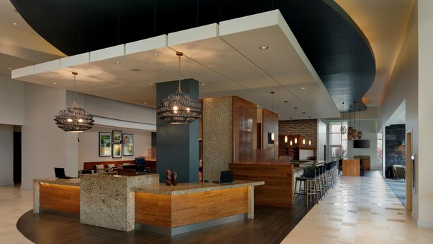 A modern hotel lobby with a reception desk, seating area, and a bar. - Hyatt Place Bayamon (Bayamon)