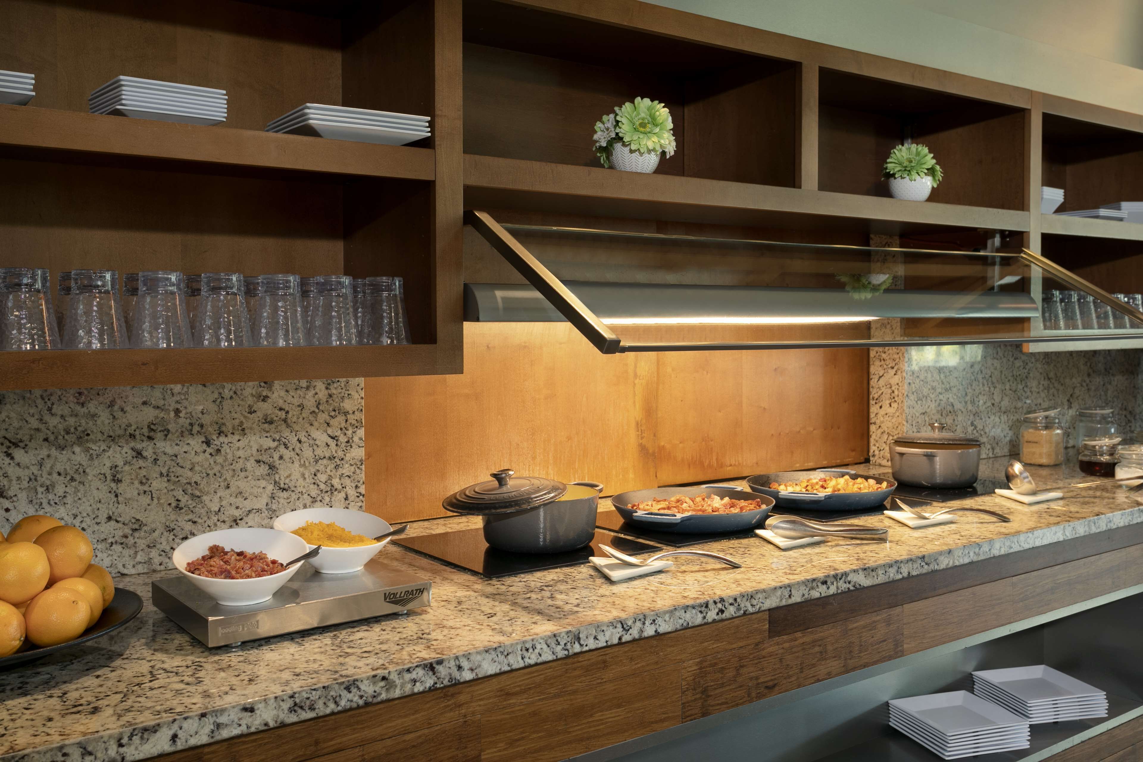 Un buffet con diversi piatti, un fornello e un espositore per bicchieri.