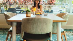 A dining area with a table, chairs, a potted plant, and a view of tropical plants outside. - Hyatt Place Bayamon (Bayamon)
