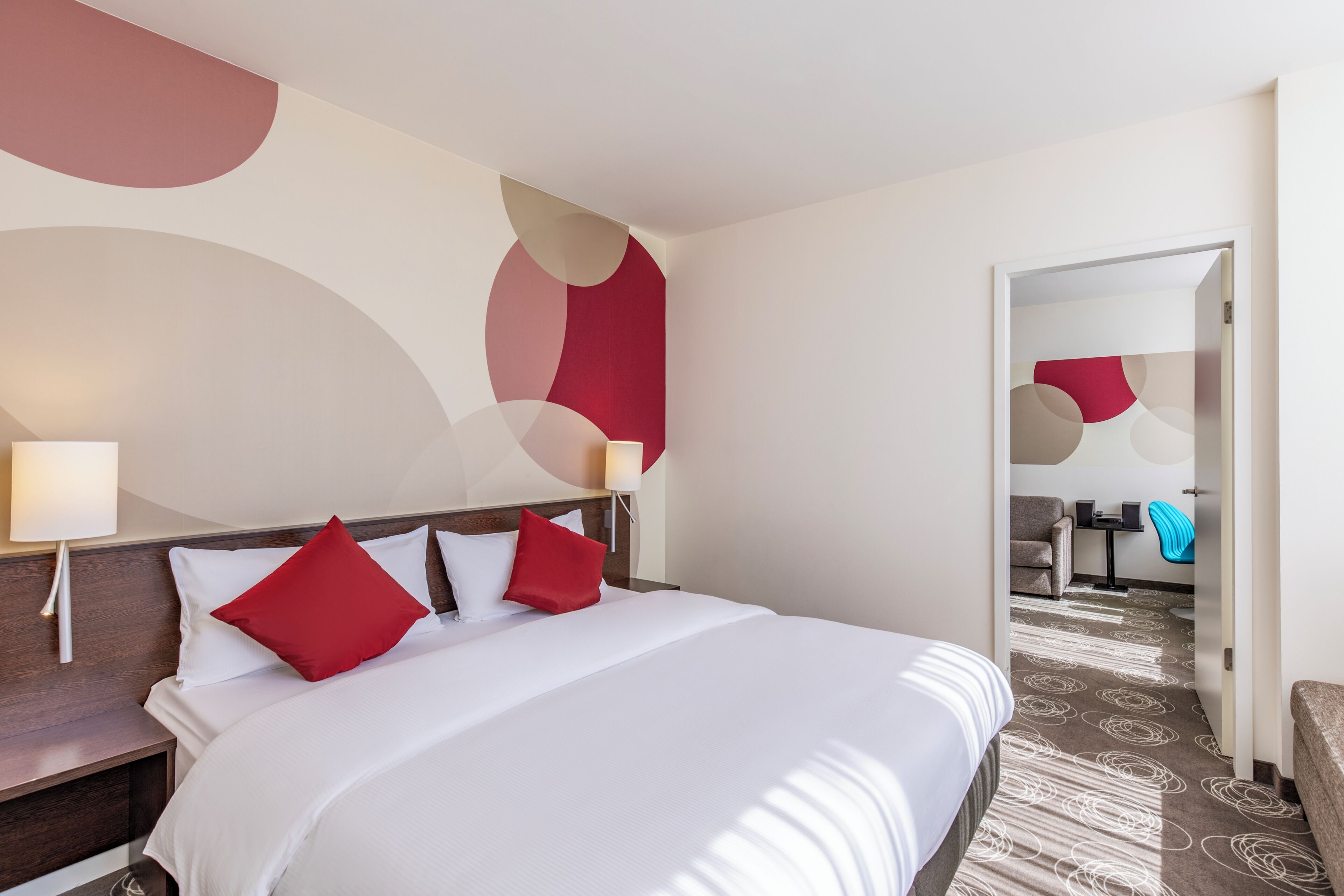 Une chambre d’hôtel avec un grand lit, une table de chevet, un bureau et une chaise.