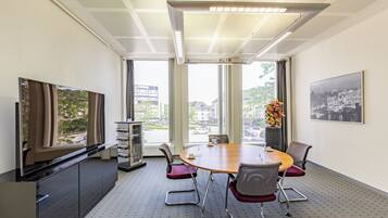 A conference room with a large table, chairs, a television, and a vending machine.