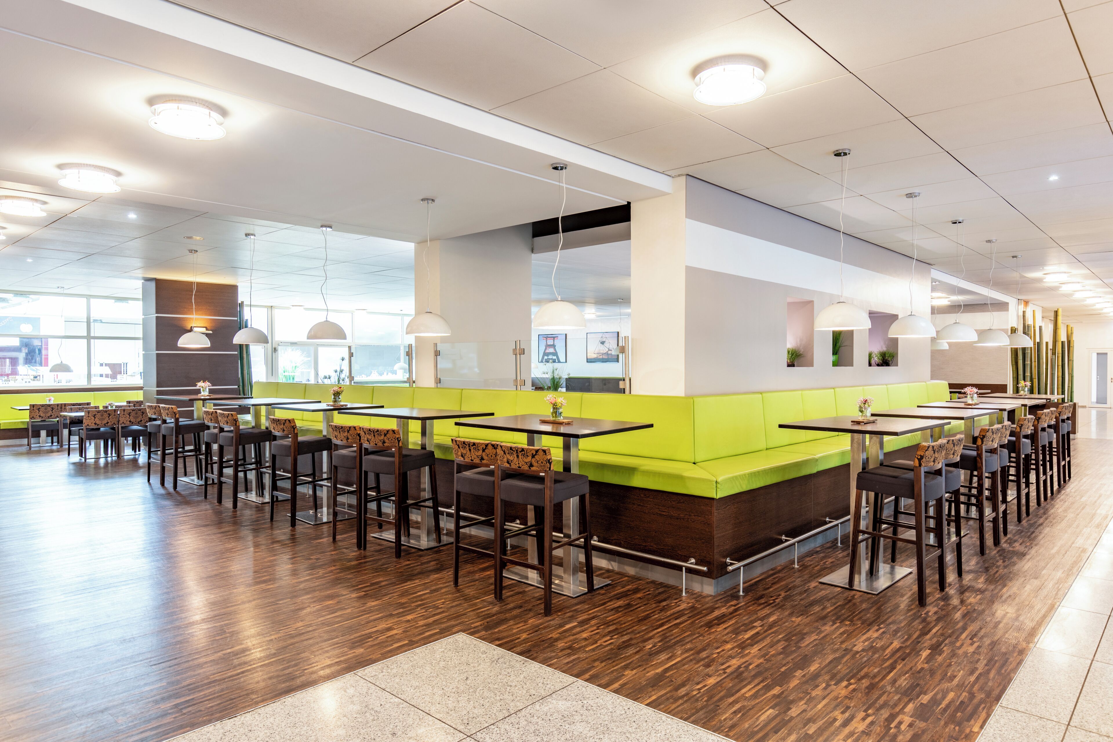 Ein modernes Restaurant mit hohen Tischen, Stühlen und einer grünen Theke.