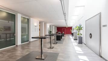A modern office space with glass walls, metal tables, and a red accent wall.