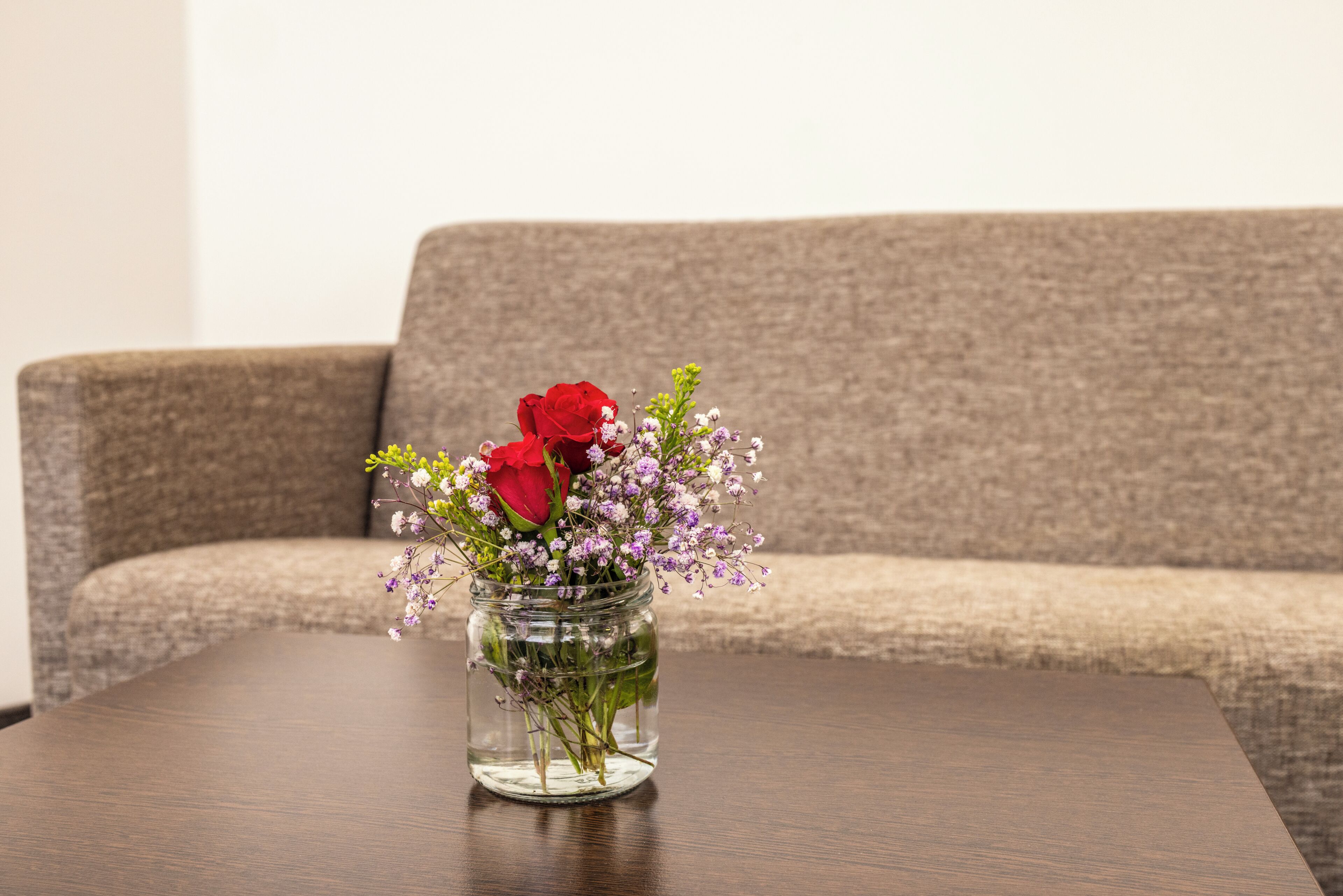 En klar glasvase med blomster på et træbord.