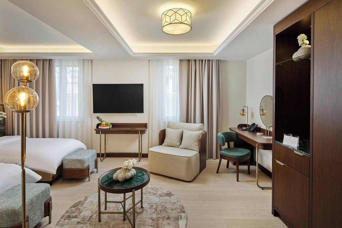 A hotel room with a bed, sofa, desk, and a TV.