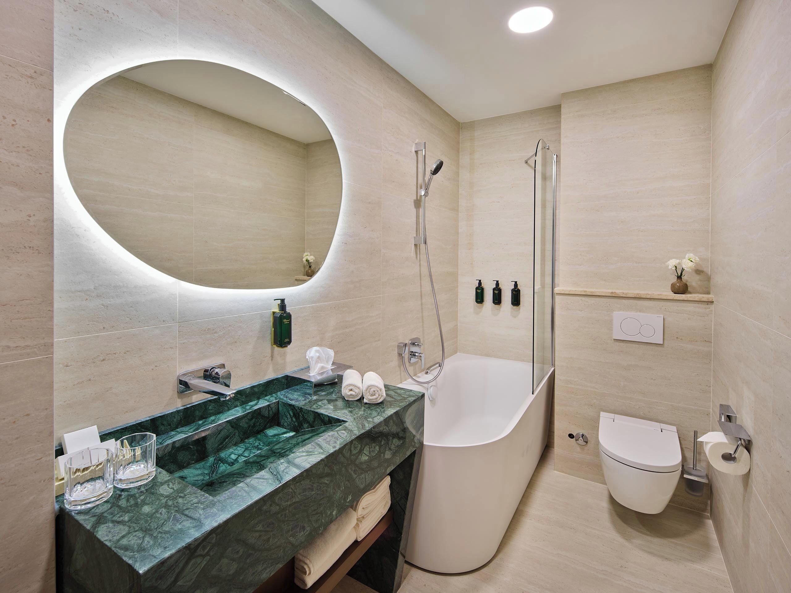 A modern bathroom with a freestanding bathtub, a large mirror, and a marble sink.