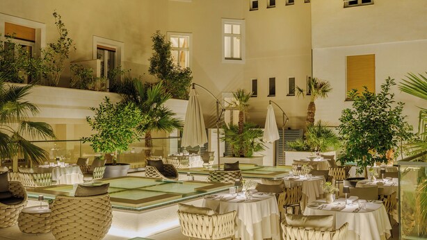 A spacious indoor dining area with multiple tables and chairs, surrounded by lush greenery and potted plants. - Palazzo President (Split)