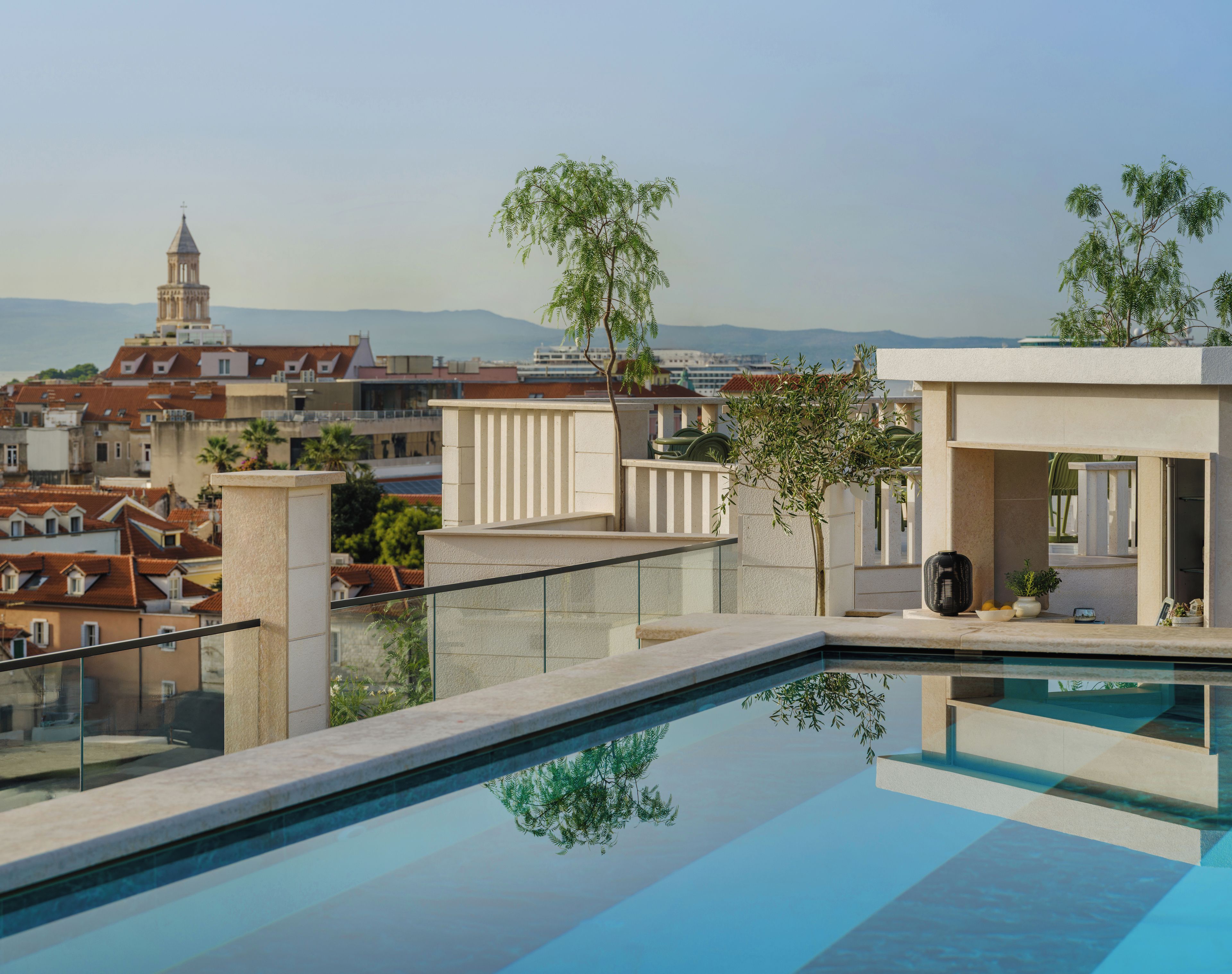 A rooftop pool with a clear view of the cityscape and distant mountains.