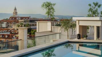 A rooftop pool with a clear view of the cityscape and distant mountains.